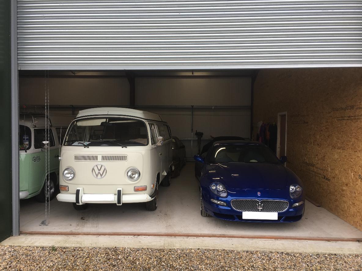 Showcasing a modern vehicle storage unit inside, with a blue Maserati and a cream Vw camper van.